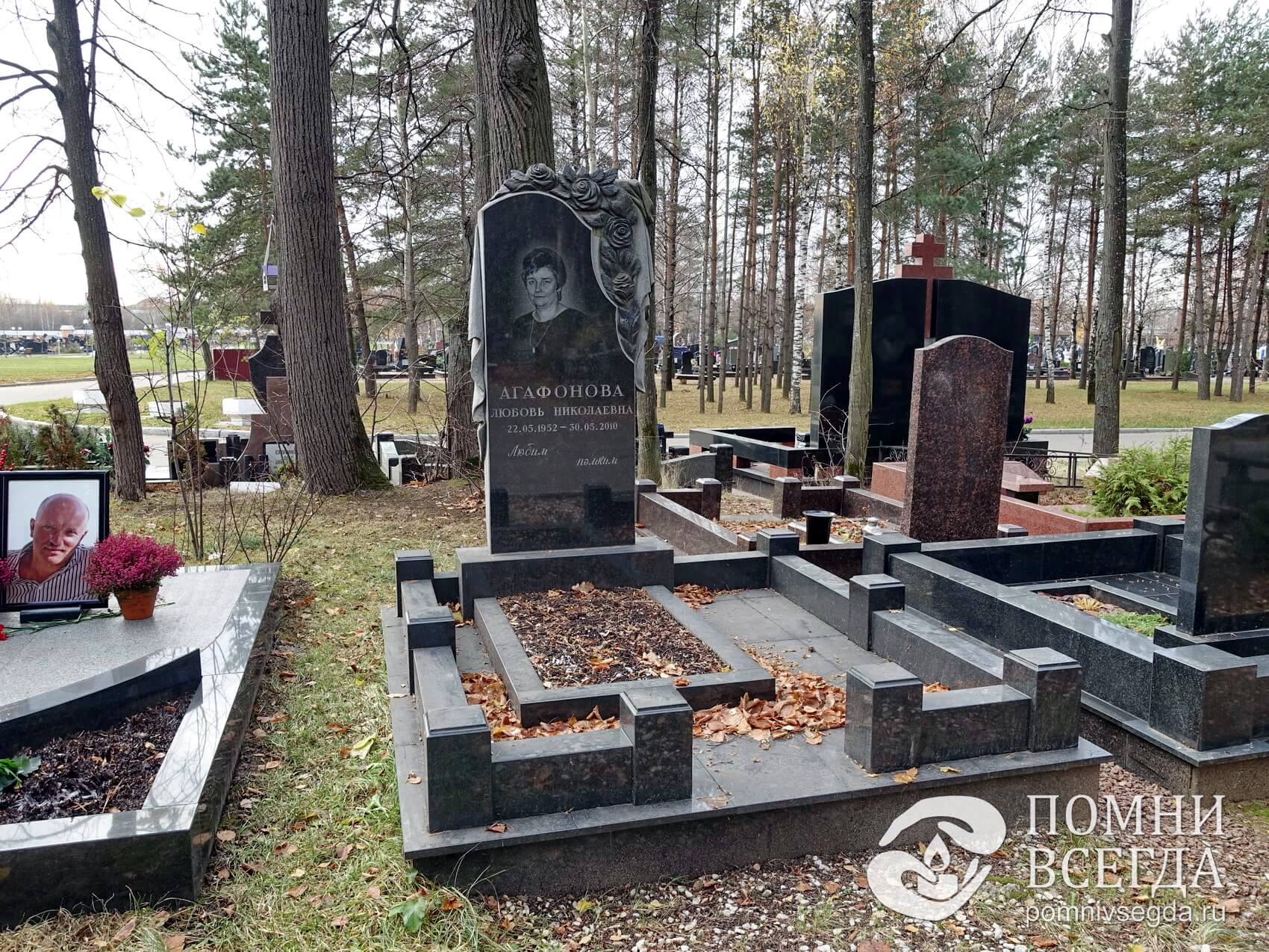 Вертикальный памятник из гранита с траурным покрывалом и цветочными бутонами